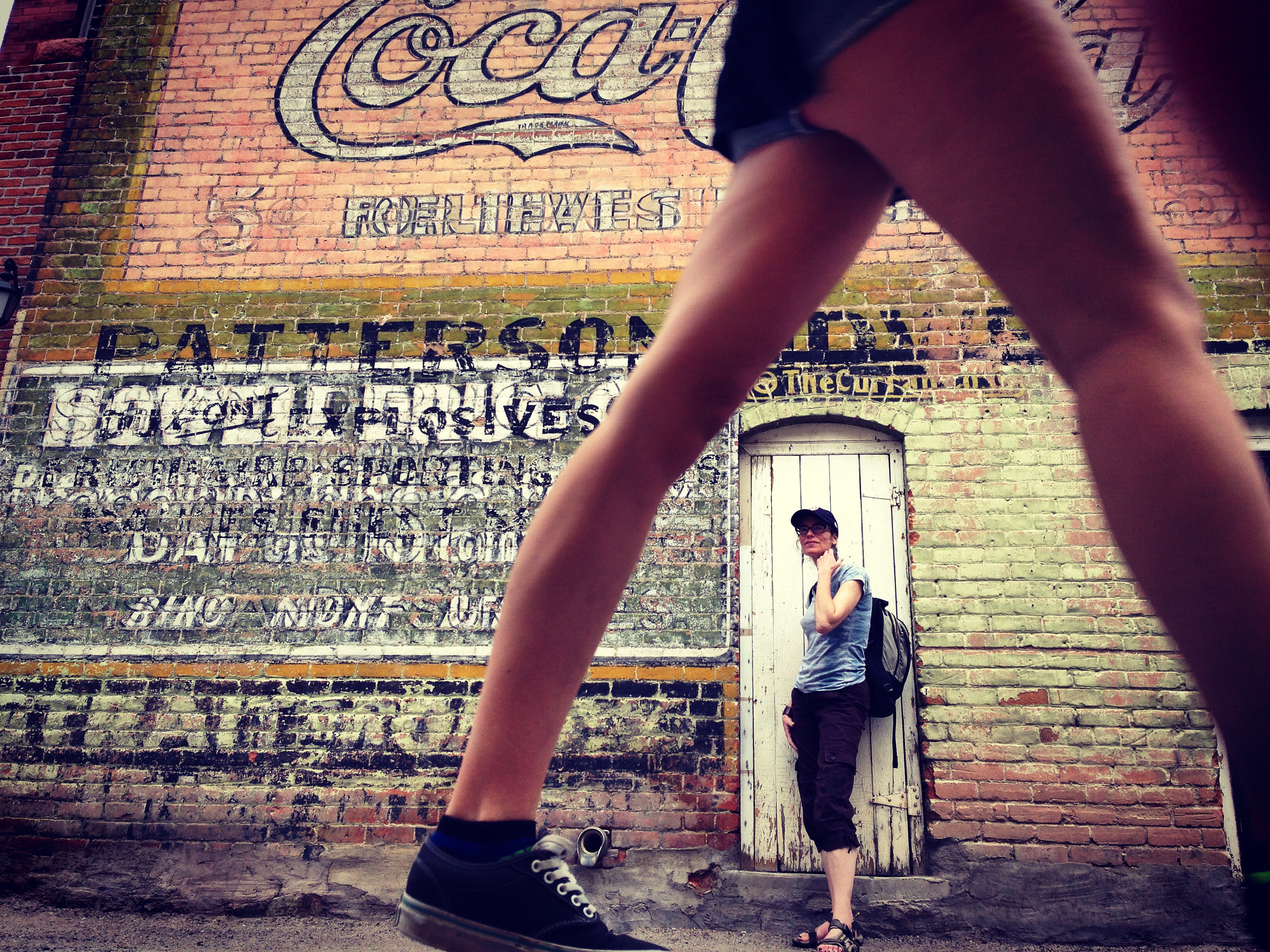 two women in salida, colorado. legs and brick wall.