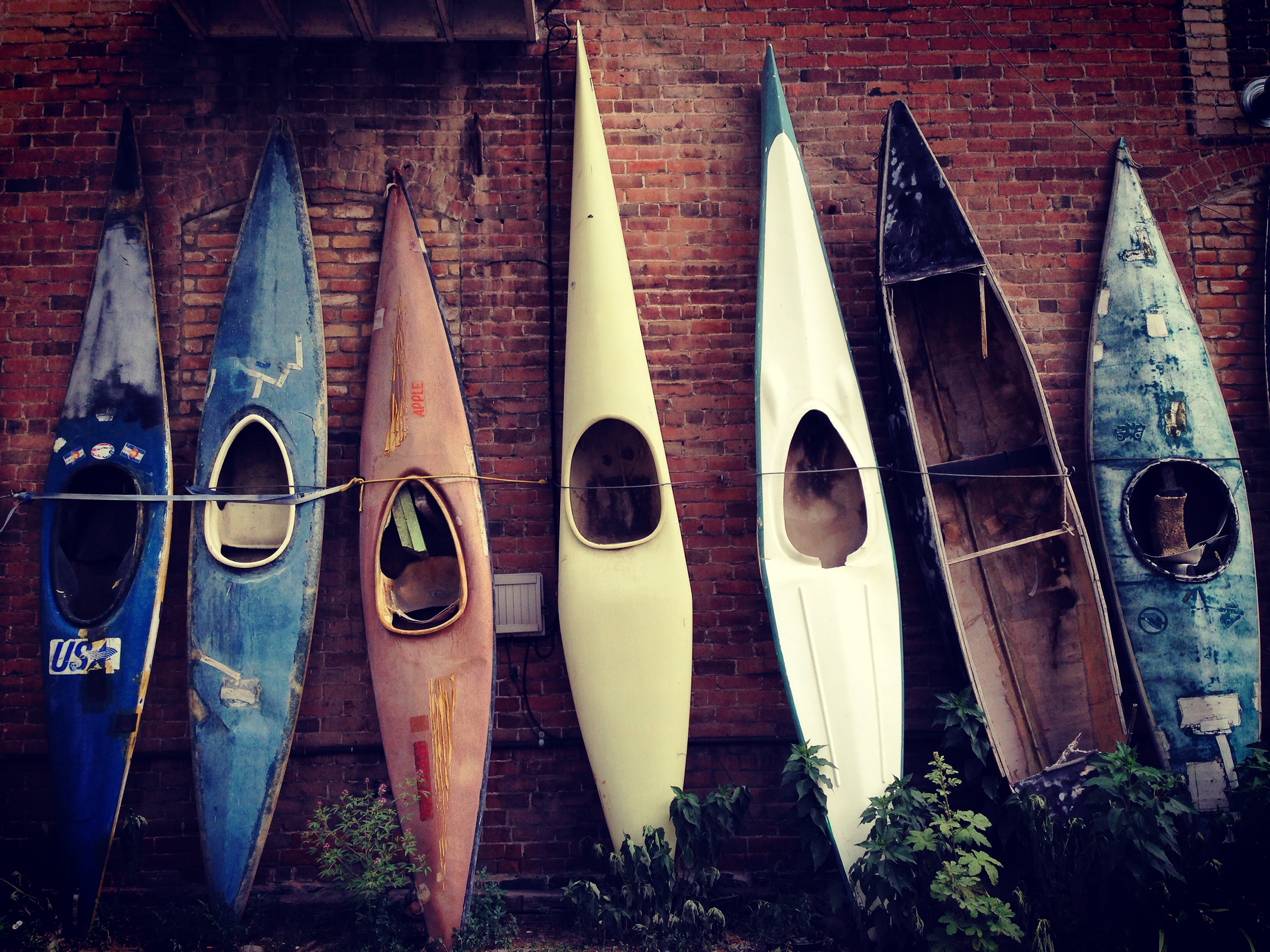 seven kayaks against brick wall in salida, colorado.