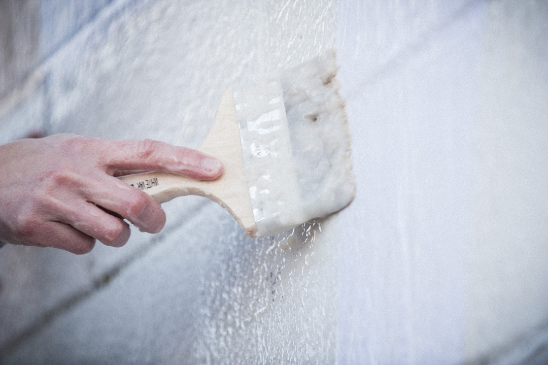 Artist Anne Smith working on her wheat-paste art piece on the cinderblock wall at the Finding A Line skate bowl in DC.