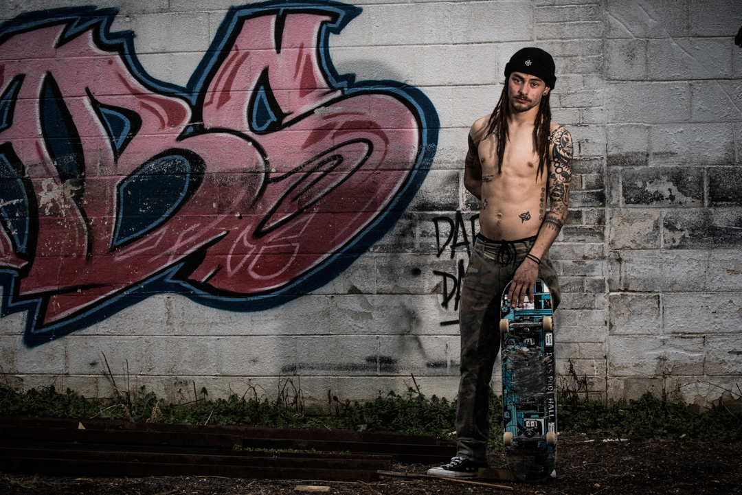 Brandon Lee Padayao shows off his body art next to some wall art. Tattoos and graffiti at the Finding A Line bowl in DC.