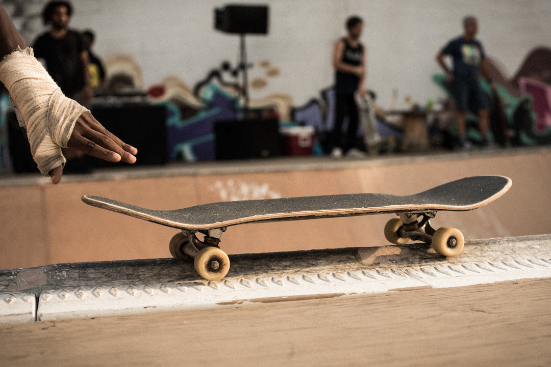 A bandaged wrist and hand retrieves skateboard.