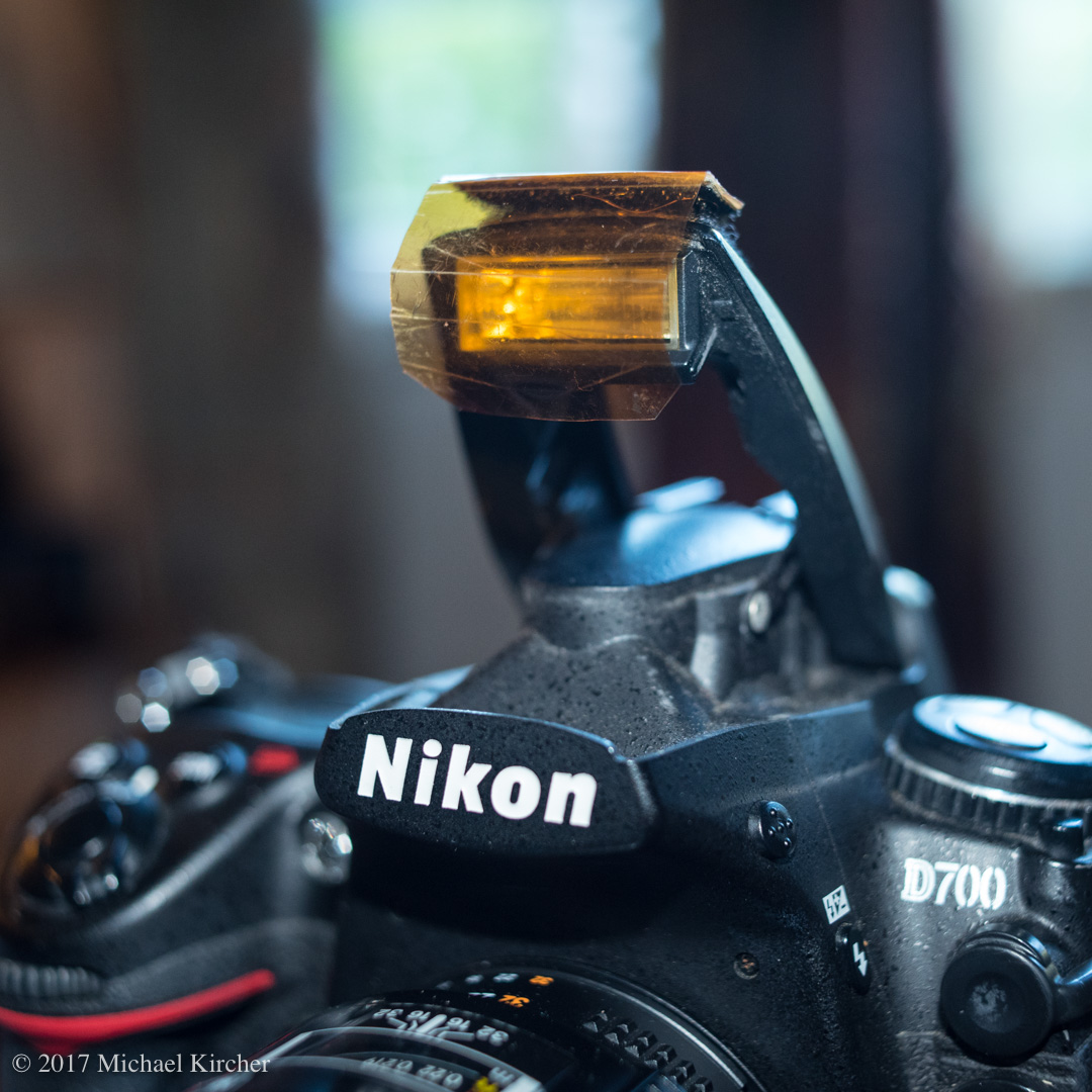 Amber gel affixed to the pop-up flash of a Nikon D700 using custom cut velcro strips.