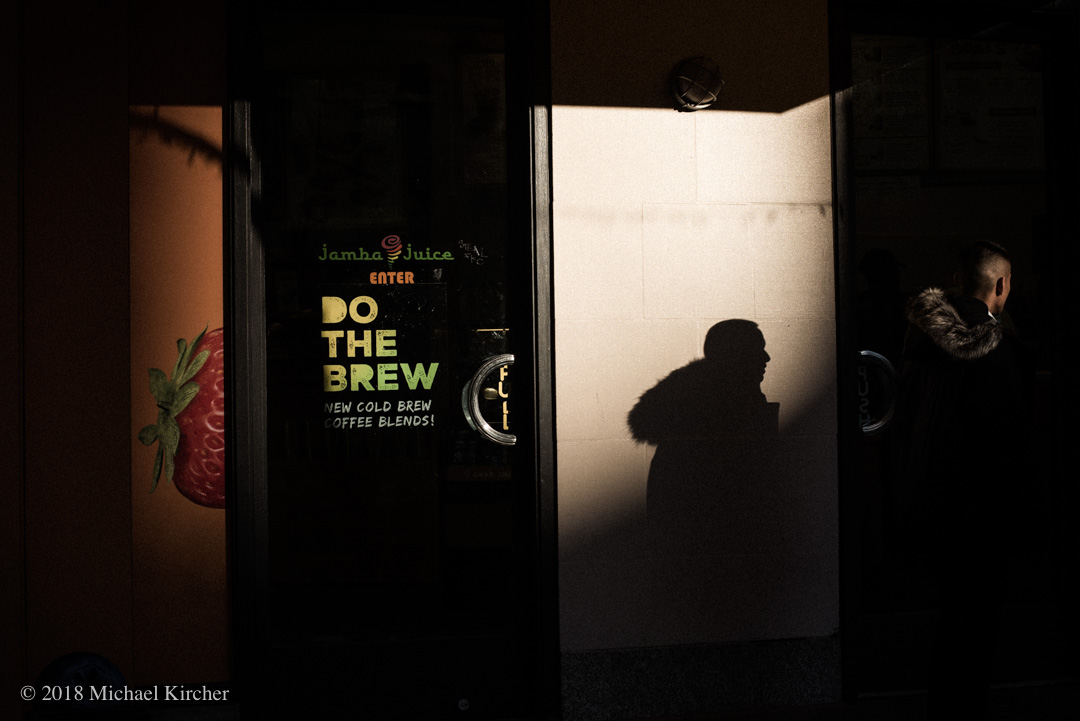 Late afternoon light and shadow of a young man in front of Jamba Juice in Washington DC.