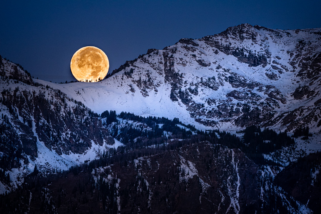 Full moon appears to rest upon the Grand Teton range.