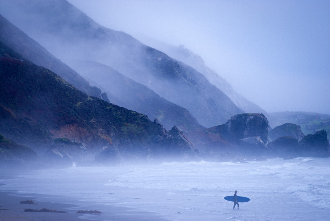 Surfer entering water at Stinson Beach on a misty morning in December, 2012.