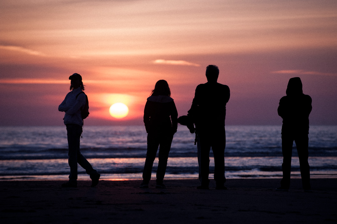 Four people silhouetted against a beautiful sunset at Stinson Beach, California.